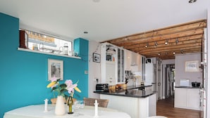 A modern kitchen with white cabinets, a black countertop, and a wooden ceiling. - Alltwen (Porthmadog)