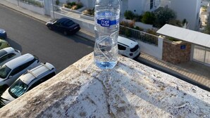 A bottle of Font Vella water on a balcony overlooking a coastal cityscape with modern buildings and parked cars. - Oceanfront Retreat in Sant Josep de sa Talaia With Shared Pool (Sant Josep de sa Talaia)
