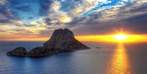A coastal landscape with a prominent rock formation and the sun setting over the horizon. - Oceanfront Retreat in Sant Josep de sa Talaia With Shared Pool (Sant Josep de sa Talaia)