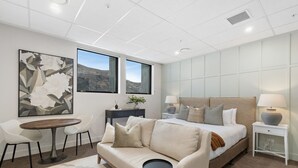 Une chambre moderne avec un grand lit, un canapé, une table à manger et une vue sur les montagnes.