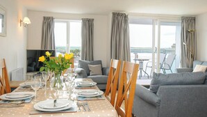 A dining area with a table set for four, a sofa, and a TV in the corner.