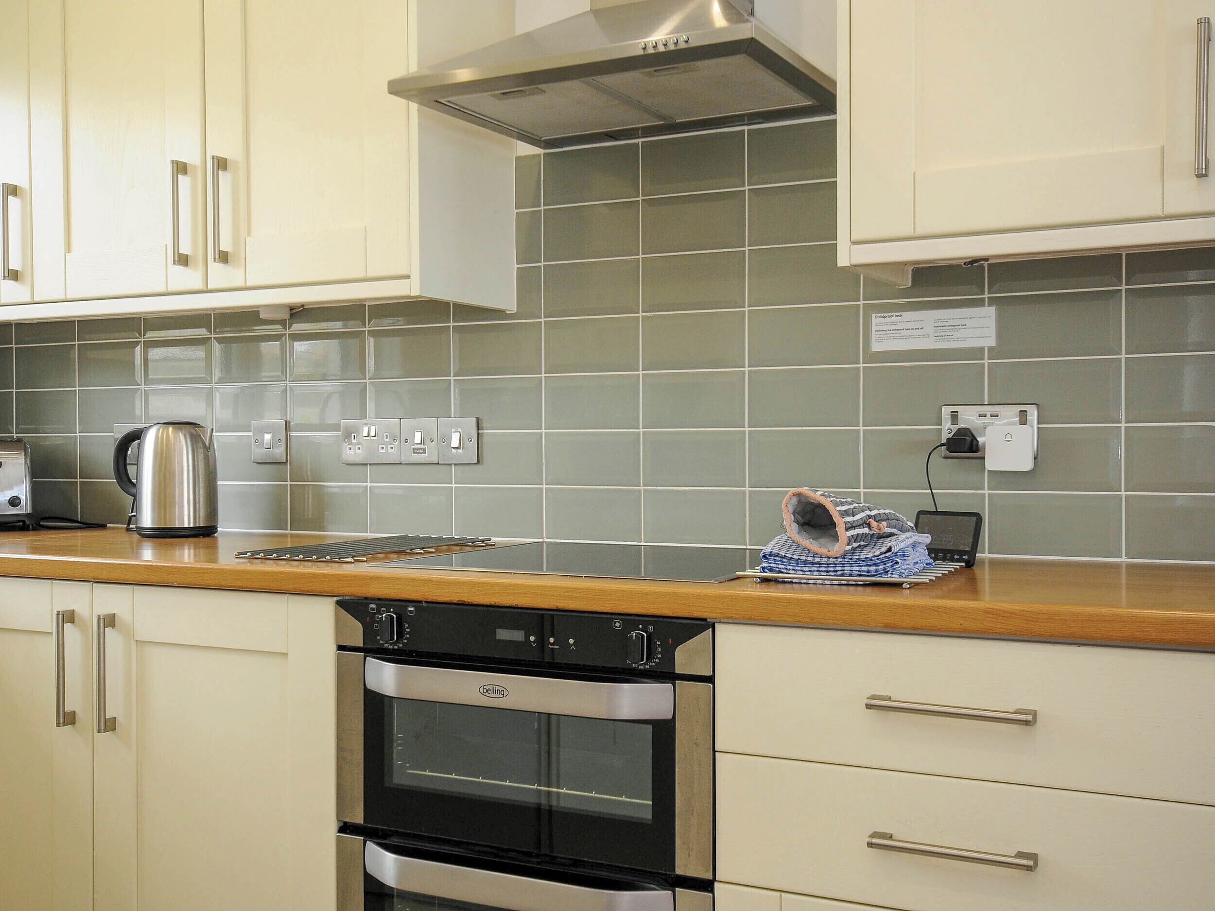 A kitchen with white cabinets, a stainless steel range hood, a kettle, a toaster, and a portable heater.