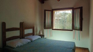 A bedroom with a wooden headboard, a single bed, a nightstand, a lamp, and a window with curtains. - Charming House in Sassari With Ocean Views (Arzachena)