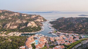 A coastal town with a marina, terraced houses, and a mountainous backdrop. - Charming House in Sassari With Ocean Views (Arzachena)