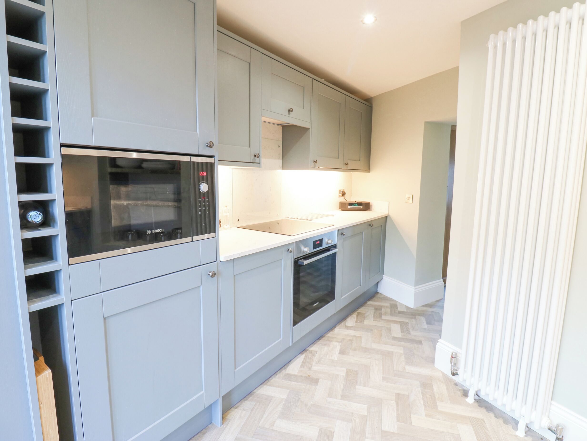 A modern kitchen with grey cabinets, a Bosch microwave, and a built-in oven.