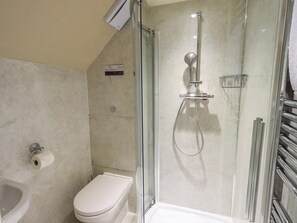 Un baño moderno con ducha de vidrio, inodoro y secamanos.