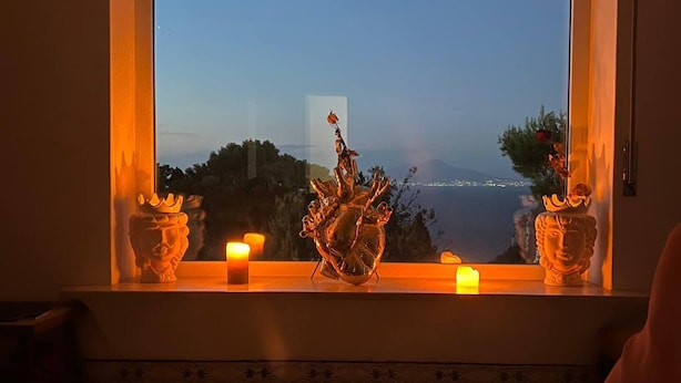 A room with a large window, a bed, and decorative items including a heart-shaped sculpture and a statue. - Heartbreaking sea View House in Capri - Italy (Capri)