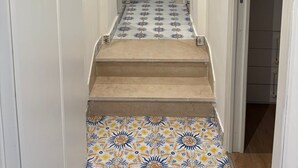 A narrow hallway with a tiled floor leading to a room with a white cabinet and a black object on the wall. - Heartbreaking sea View House in Capri - Italy (Capri)