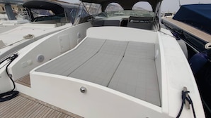 A boat deck with a covered seating area, a small table, and a rope coiled on the side. - Fall in Love With the Amalfi Coast Charming Boat Rental in Naples (Naples)