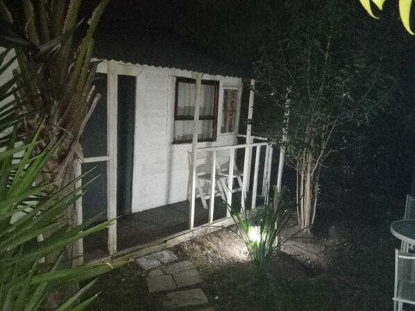 A small, white building with a porch and a single window.