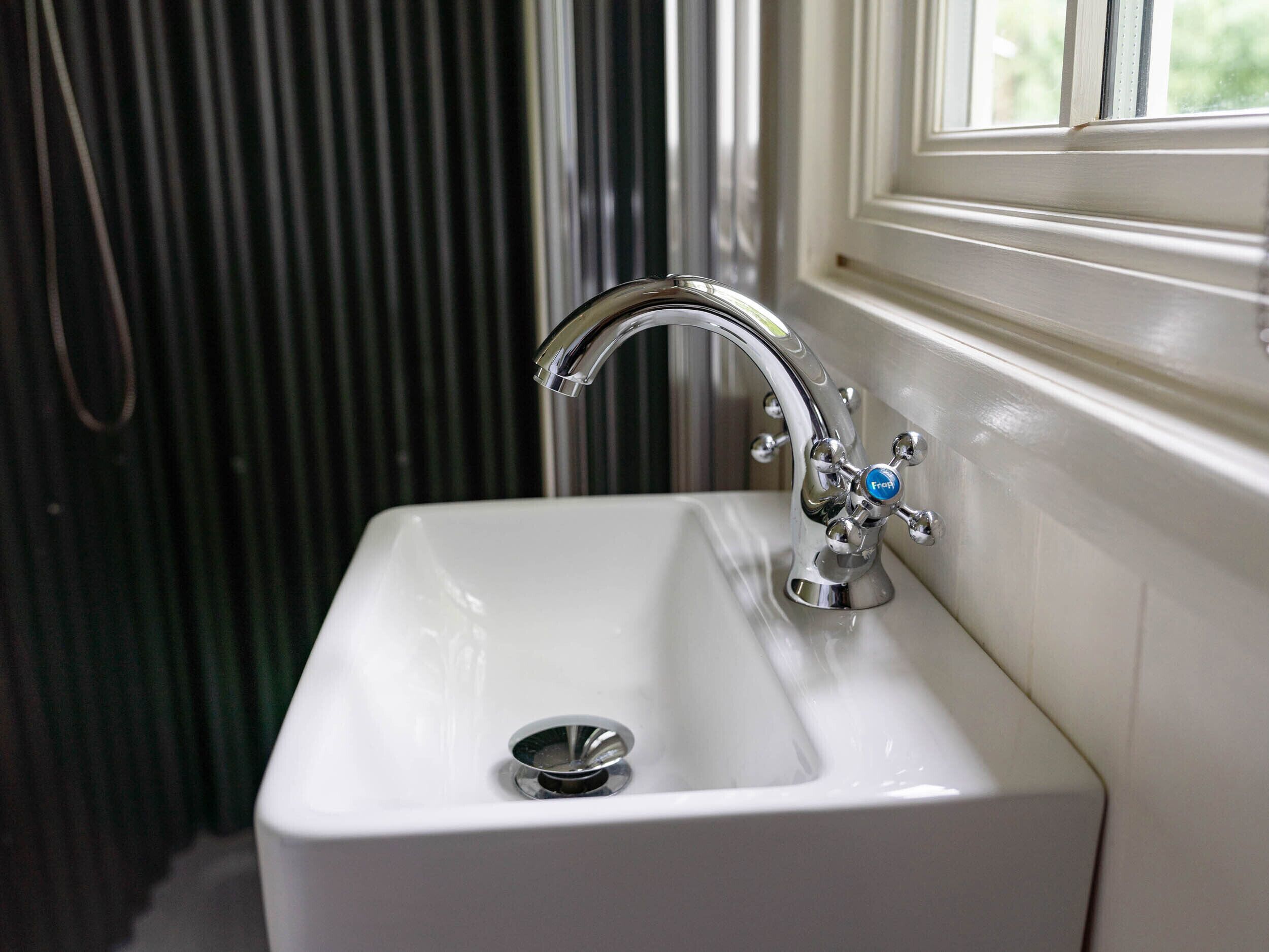 A white bathroom sink with a chrome faucet and a single basin.