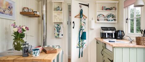 A cozy kitchen with wooden cabinets, a coffee machine, and a hanging apron.