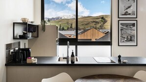 Une cuisine moderne dotée d’une grande fenêtre donnant sur un paysage montagneux.