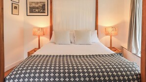 A bedroom with a large bed, two bedside lamps, a canopy bed, and framed pictures on the wall. - Tower Cottage (Windermere)