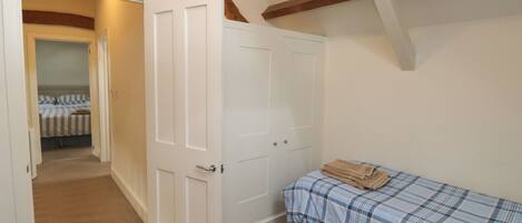 Un dormitorio con cama, una puerta que da a otra habitación y vigas de madera a la vista en el techo.