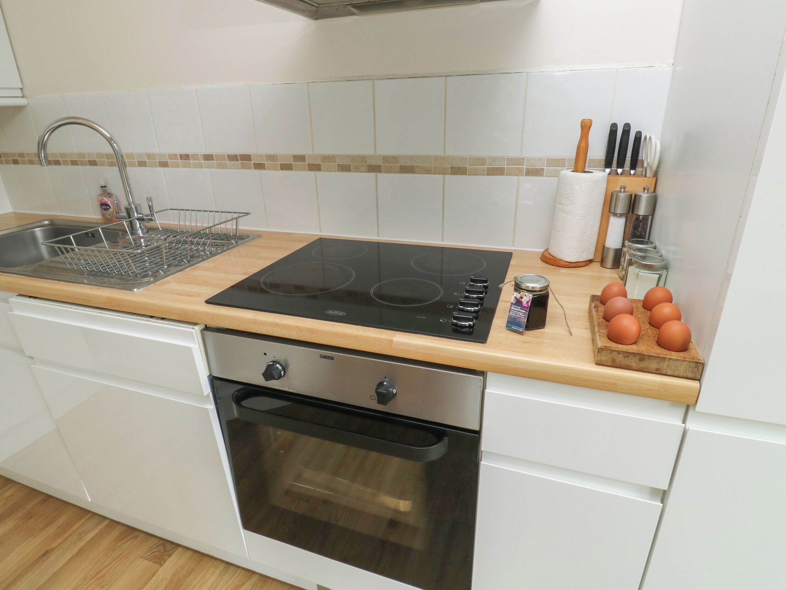 A kitchen with a sink, stove, oven, and a wooden countertop.