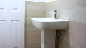 A bathroom with a white sink, a chrome faucet, and beige tiles.