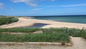 A beach with a sandy path leading to the water, surrounded by green vegetation. - Bella's Beach Cottage (Fraserburgh)