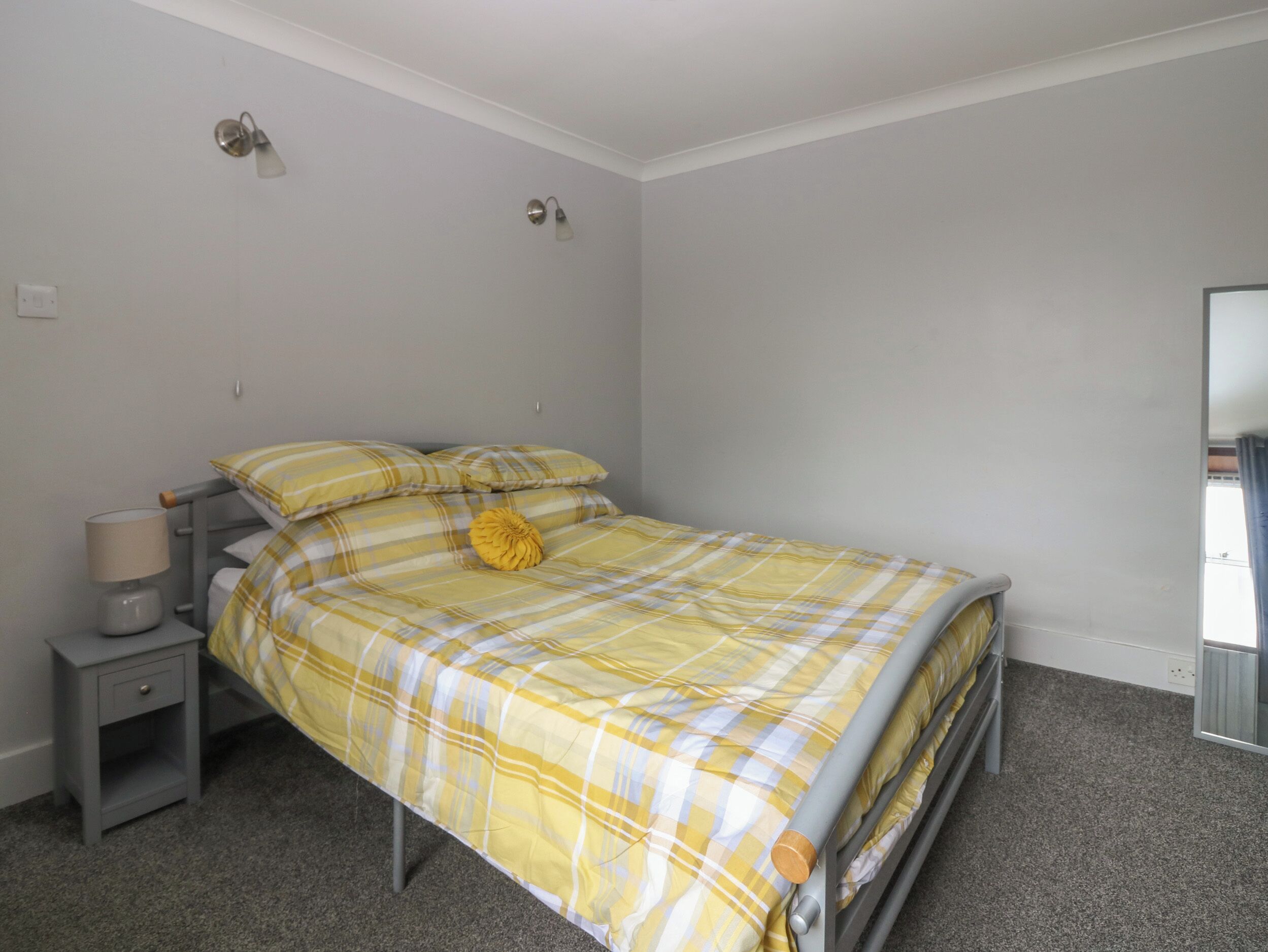 Une chambre à coucher comprenant un lit, une table de chevet, une lampe et un luminaire fixé au mur.