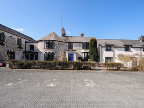 A traditional stone building with a blue door, arched windows, and a chimney. - Sycamore Apartment (Lifton)