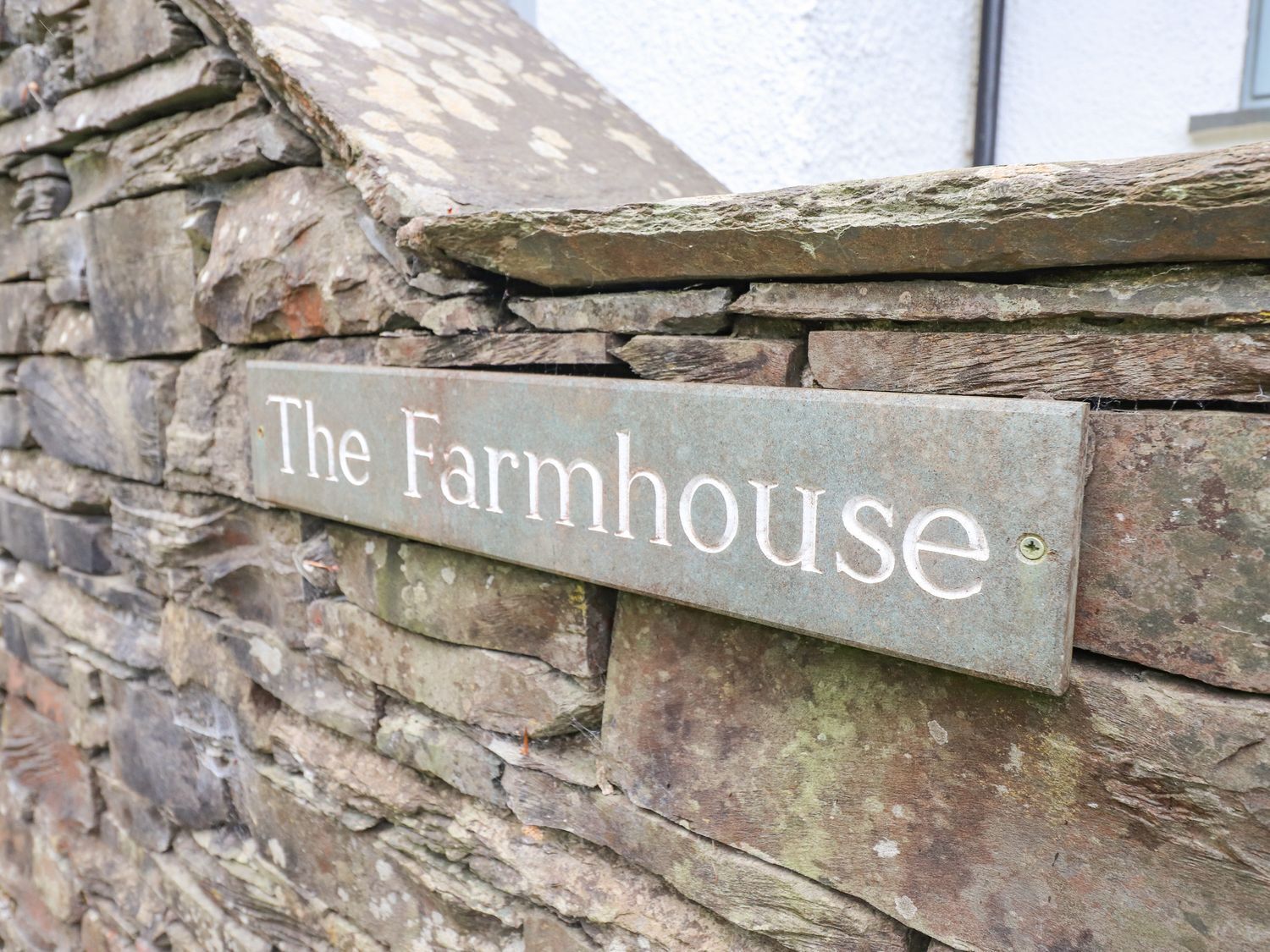 Un muro de piedra con un letrero que dice "The Farmhouse".