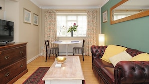 A living room with a television, a dining table, a sofa, and a large mirror. - Alway (Lifton)