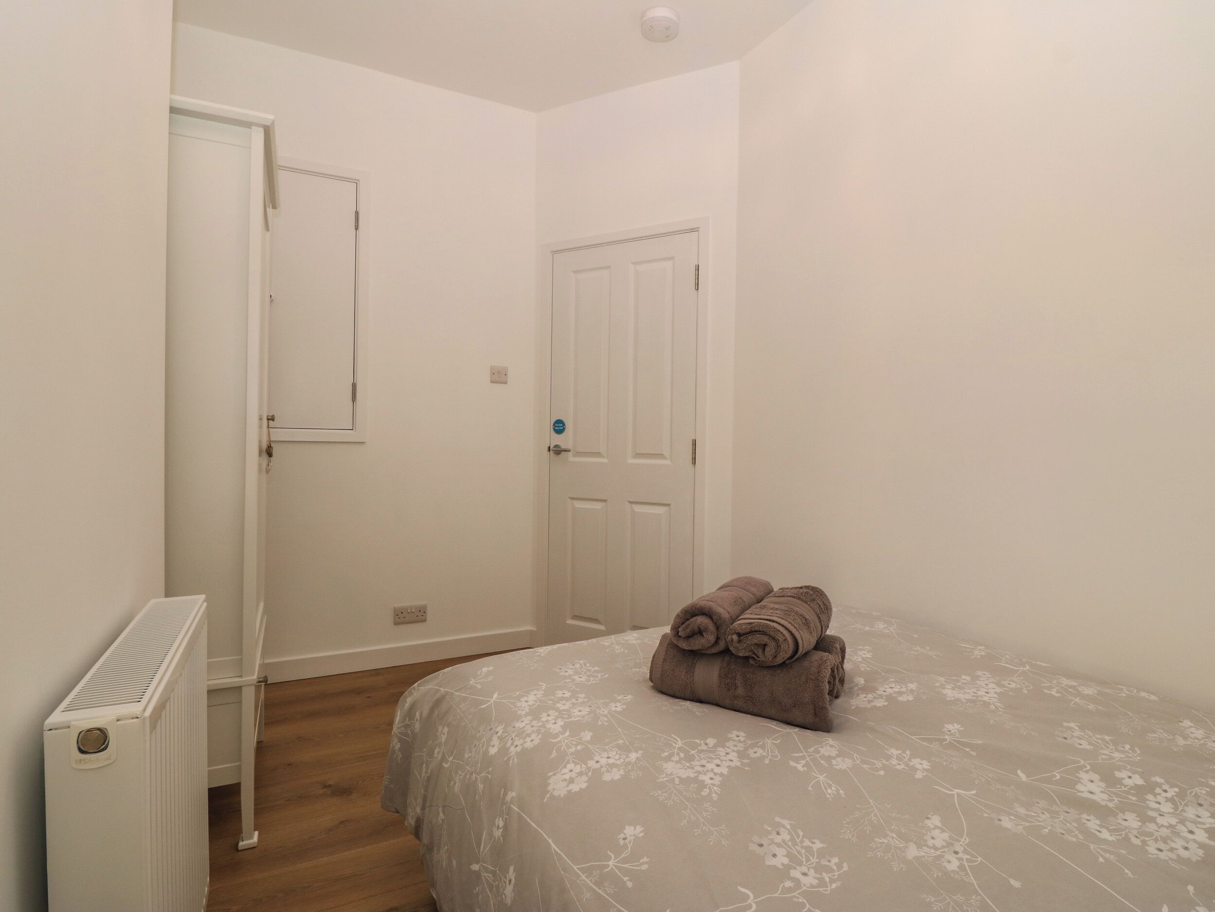 Ein Schlafzimmer mit einem Bett, einem Heizkörper und zwei Türen.
