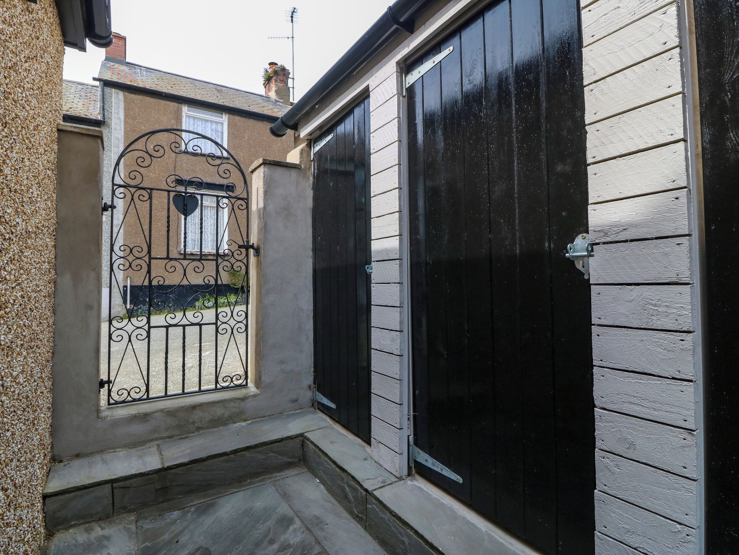 A narrow pathway leading to a gated entrance with a decorative iron gate.