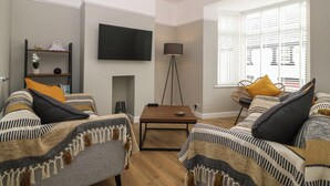 A living room with two sofas, a TV, a floor lamp, and a bookshelf. - Elsinore (Conwy)