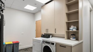 Un cuarto de lavandería con lavadora, secadora y armarios de almacenaje.