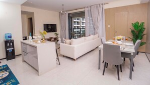 A modern living room with a sofa, dining table, and kitchen area. - Executive 1 Br -Gtc with gym & Pool (Nairobi)