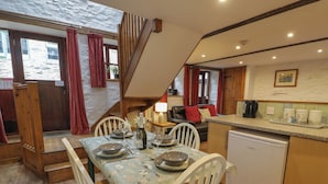 A cozy dining area with a wooden table set for four, a sofa, and a kitchen area with a dishwasher.
