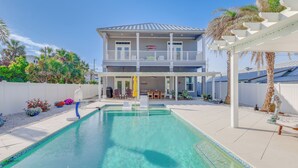 Une maison à deux étages dotée d’une piscine, d’un espace extérieur aménagé et d’un patio couvert.