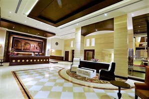 A lobby with a checkered floor, a reception desk, and seating areas. - Golden Galaxy  (Ballabgarh)