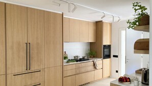 A modern kitchen with wooden cabinets, a built-in oven, and a countertop with a kettle and fruit. - Villa with swimming pool in front of the sea (Roda de Berà)