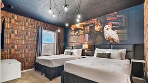 Ein Schlafzimmer mit zwei Betten, einer Bücherwand und einem großen Poster.