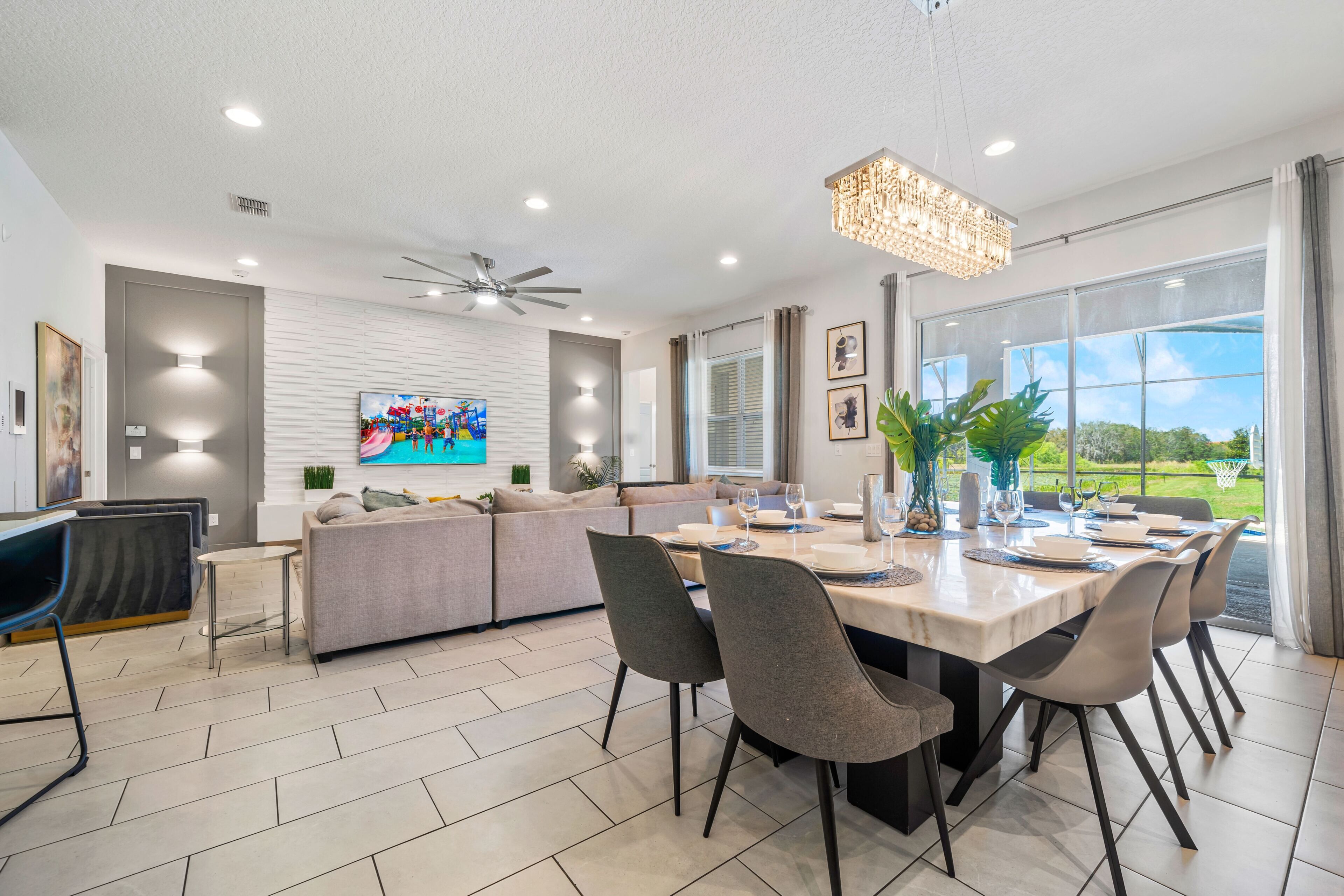 A modern dining area with a large table, chairs, and a ceiling fan.