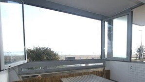 Un balcon donnant sur la plage, une clôture en bois et une table en métal avec des chaises.