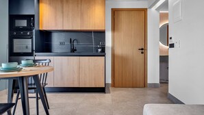 Eine moderne Küche mit Holzschränken, einer schwarzen Arbeitsplatte und einem Essbereich mit rundem Tisch und Stühlen.