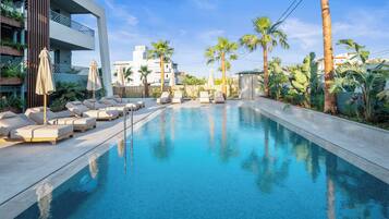 A swimming pool with lounge chairs and palm trees.