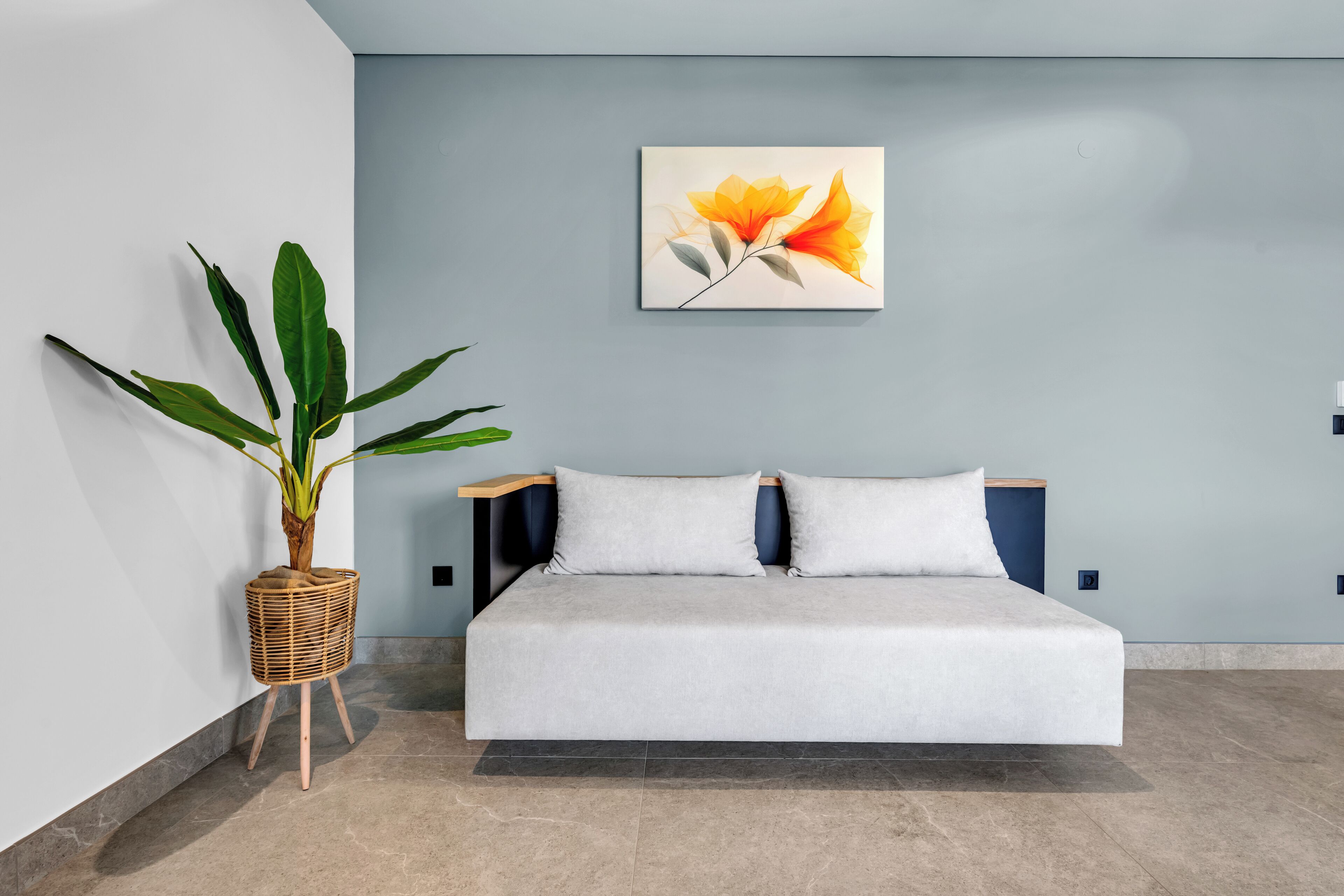 A modern bedroom with a bed, a wall-mounted painting, and a potted plant.