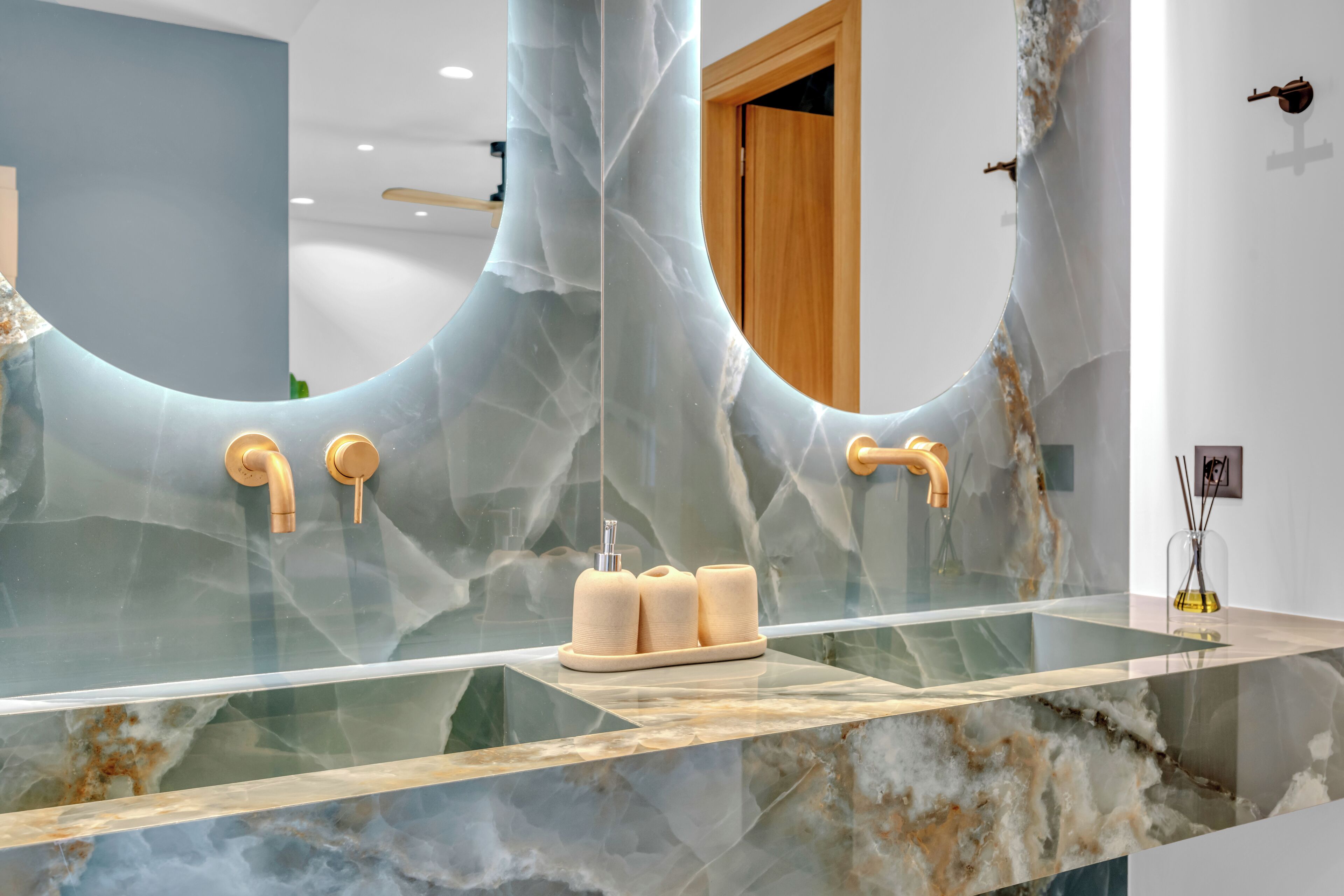 A bathroom with a large mirror, marble countertop, and modern fixtures.