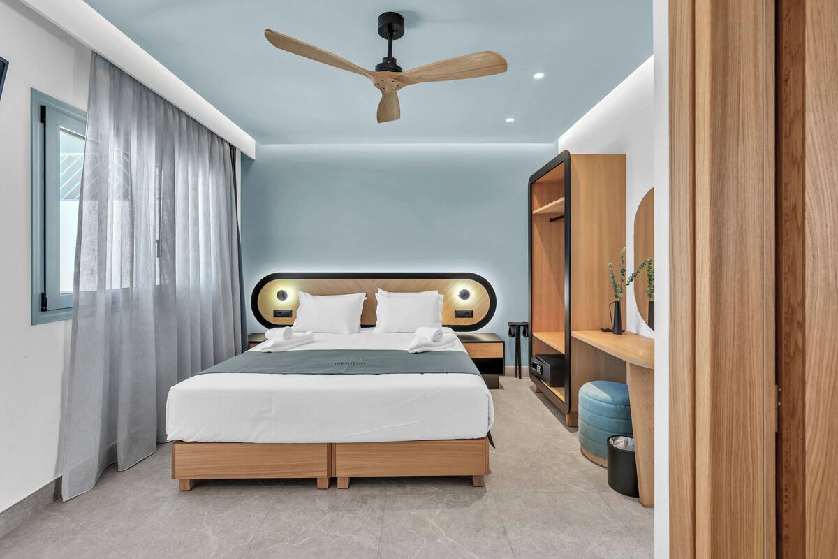 A modern bedroom with a wooden bed, a ceiling fan, a nightstand, and a wardrobe.