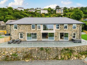 A stone building with a flat roof, large windows, and a stone wall foundation. - Plas Amherst (Harlech)