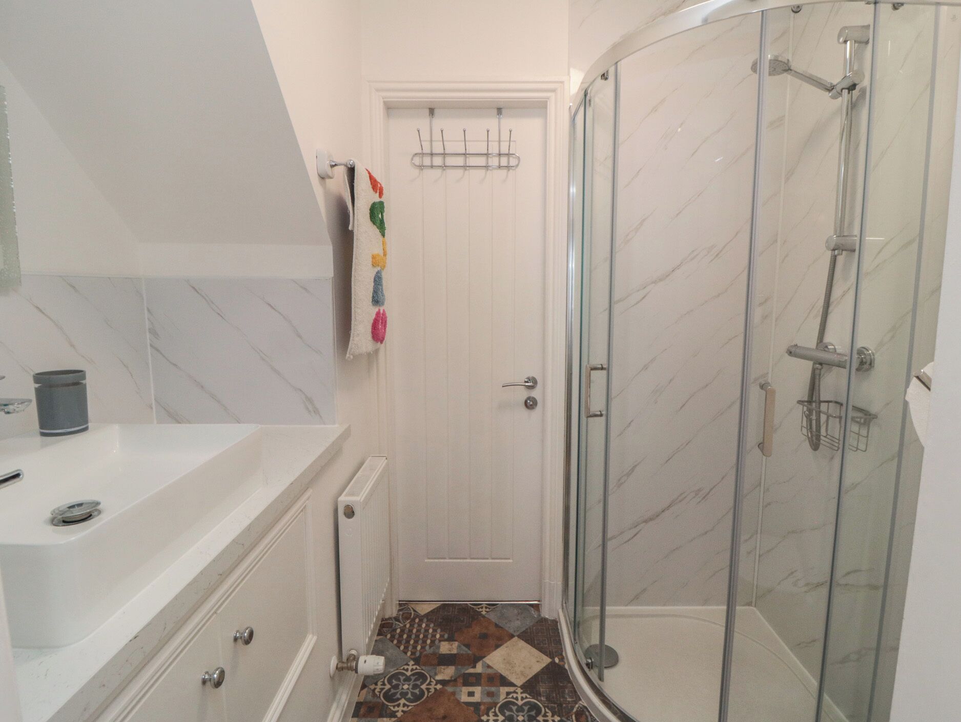 A bathroom with a shower, a sink, and a door.