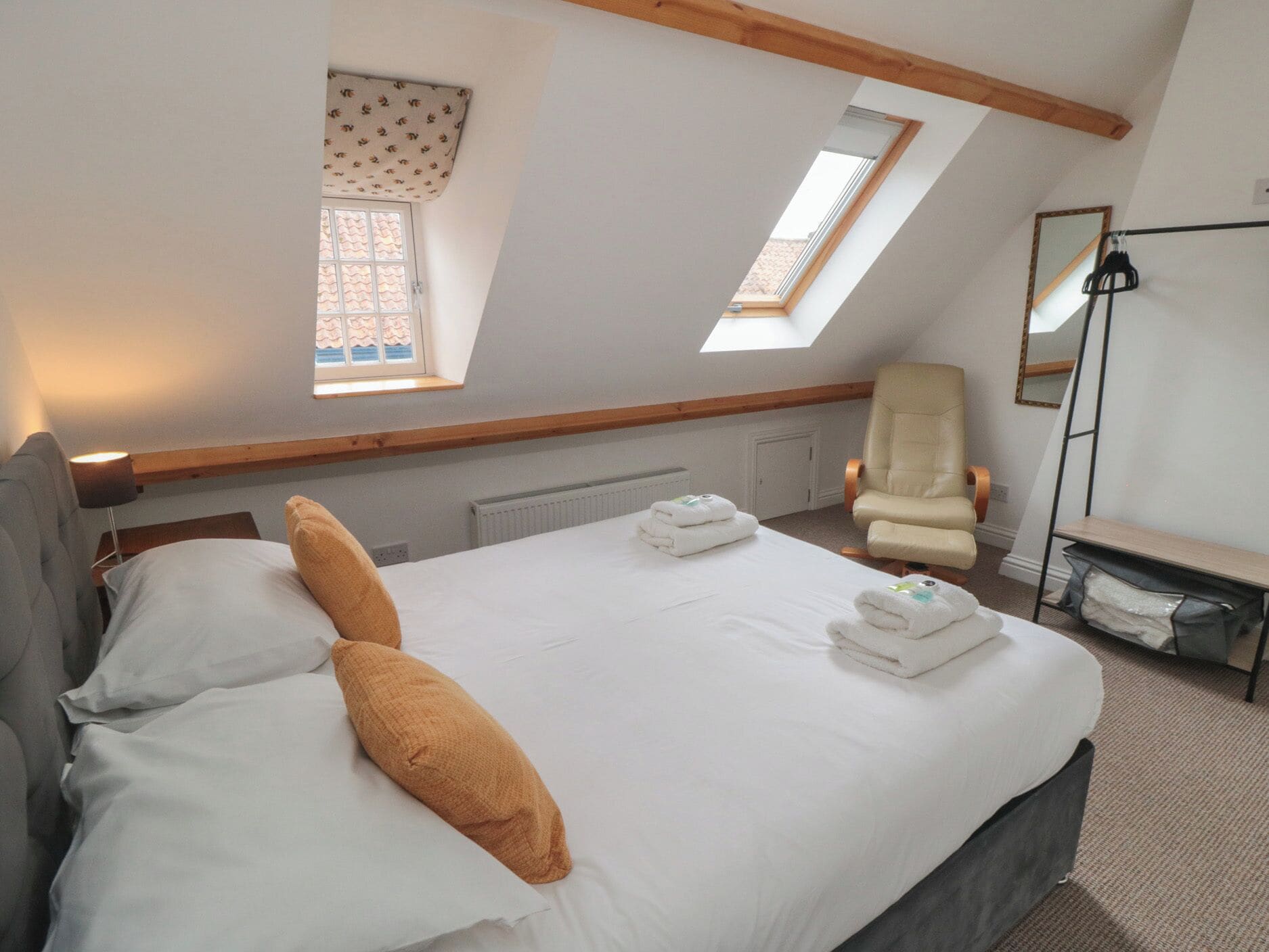 A bedroom with a bed, pillows, a chair, a desk, and a window.