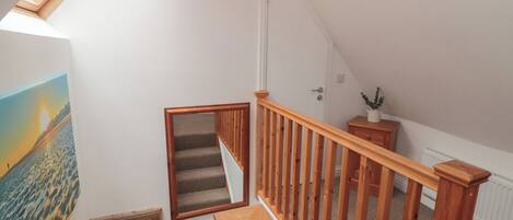 A wooden staircase with a handrail, a small wooden bench, a radiator, and a wall-mounted light fixture.