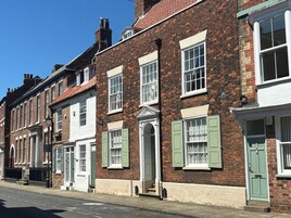 Una hilera de edificios tradicionales de ladrillo con fachadas blancas y contraventanas verdes.
