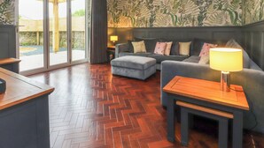 A modern living room with a herringbone wooden floor, a grey sofa set, and a wooden coffee table. - The Oakroyd (Carnforth)