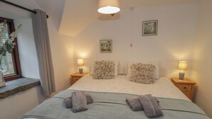 A bedroom with a bed, two nightstands, a window with curtains, a hanging lamp, and two framed pictures on the wall. - Graig Las The Stables (Oswestry)